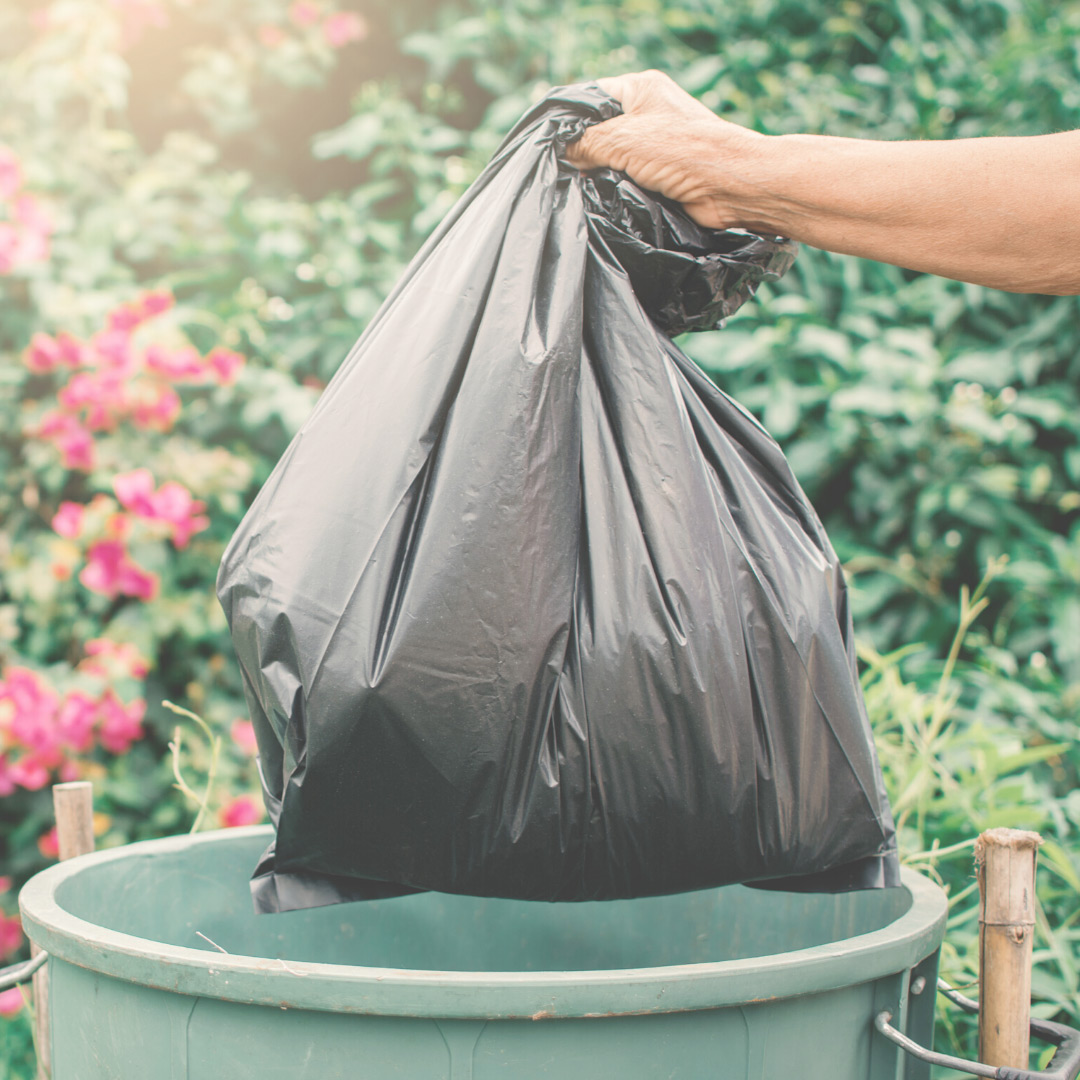 Hand disposing trash bag in a trash bin